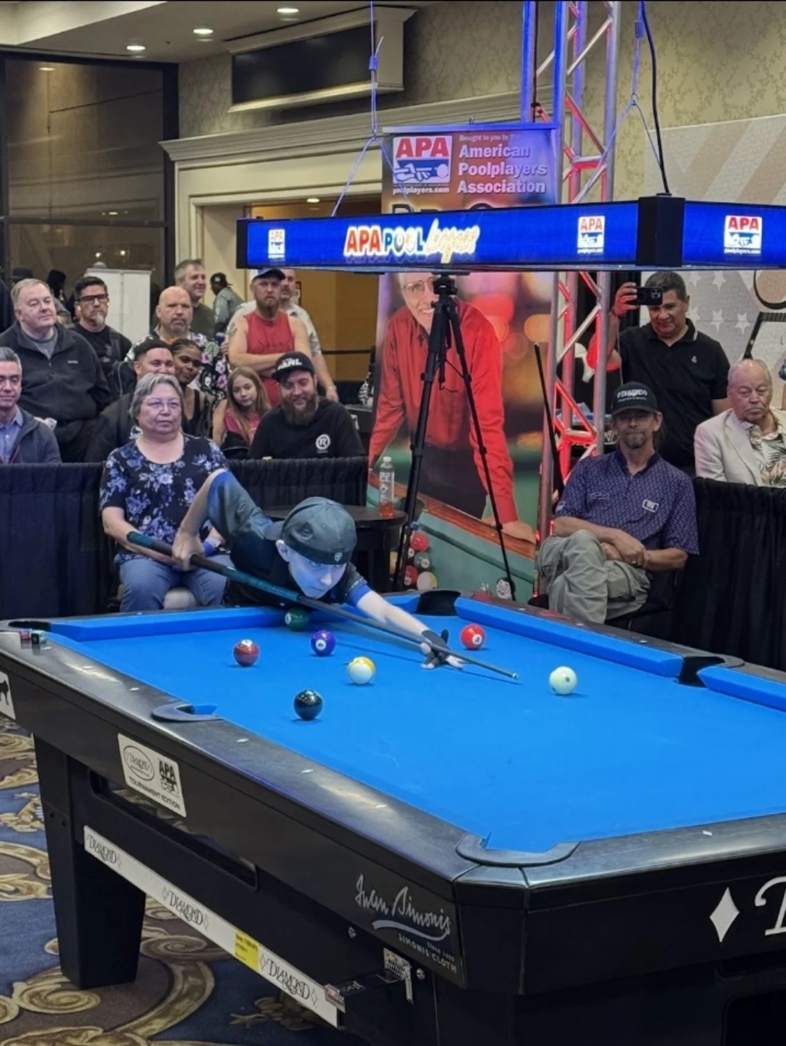 Austin aiming across a blue pool table